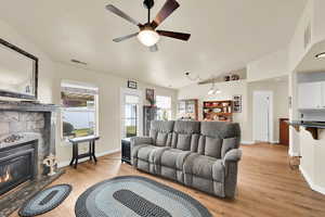 Living room with light wood-style floors, a wealth of natural light, a fireplace, and visible vents