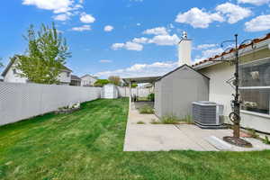 View of yard with a storage unit, a fenced backyard, an outbuilding, cooling unit, and a patio area