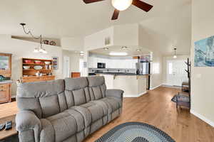 Living room featuring ceiling fan, visible vents, baseboards, and light wood finished floors