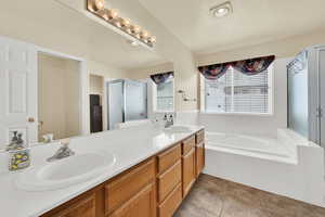 Bathroom with a sink, tile patterned floors, a stall shower, and double vanity
