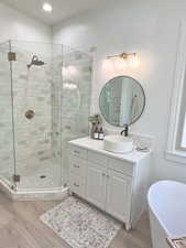 Full bathroom with vanity, a soaking tub, a stall shower, and wood finished floors