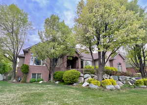 View of front of house featuring brick siding, fence, and a front yard