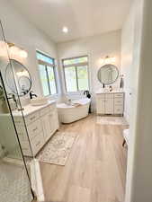 Full bath featuring a sink, wood finished floors, a stall shower, and a soaking tub