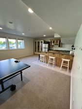 Recreation room with recessed lighting, a sink, baseboards, and light carpet