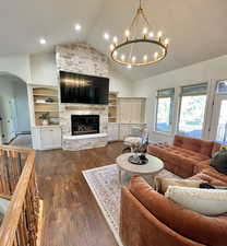 Living room featuring a healthy amount of sunlight, arched walkways, an inviting chandelier, and dark wood-type flooring