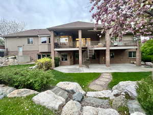 Rear view of property featuring brick siding, stucco siding, a deck, stairway, and a patio area
