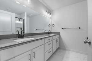 Bathroom with double vanity, baseboards, a sink, and marble finish floor