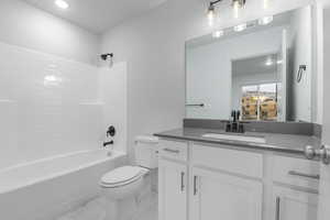 Bathroom featuring vanity, toilet, marble finish floor, recessed lighting, and shower / bath combination