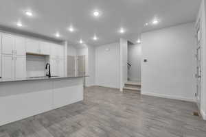 Kitchen featuring visible vents, light wood-type flooring, a sink, recessed lighting, and white cabinetry