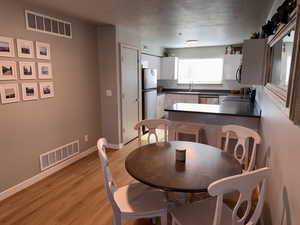 Dining room with a textured ceiling, visible vents, baseboards, and light wood-style floors
