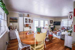 Dining room with crown molding, a heating unit, wood finished floors, and french doors