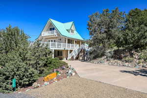 View of front of property with a porch, a balcony, stairs, and concrete driveway