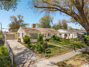 View of front facade featuring a chimney, an outbuilding, fence private yard, a detached garage, and concrete driveway