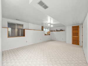 Carpeted empty room featuring visible vents