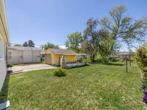 View of yard featuring concrete driveway, fence, an outdoor structure, and a garage