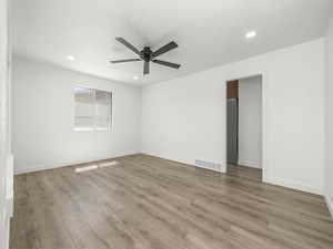 Empty room with light wood-style floors, a ceiling fan, recessed lighting, and visible vents