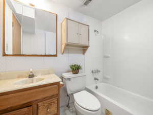 Bathroom with visible vents, vanity, toilet, and wallpapered walls