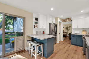 Kitchen featuring cabinetry, a kitchen breakfast bar, backsplash, and appliances with stainless steel finishes