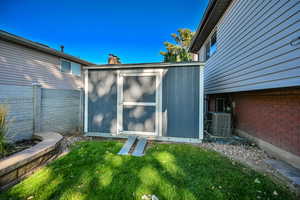 View of shed featuring fence and cooling unit