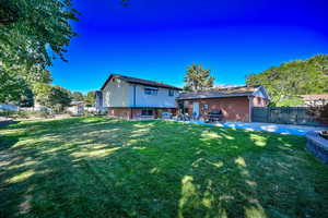 Back of house with a patio, a fenced backyard, and a yard