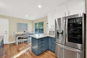 Kitchen featuring light wood-type flooring, a peninsula, light countertops, and stainless steel fridge with ice dispenser