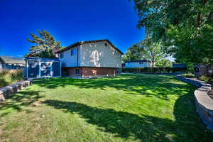View of yard featuring fence, an outdoor structure, and a storage shed