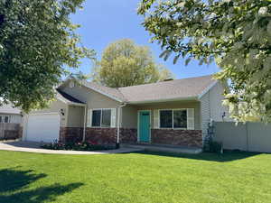 View of front of home with brick siding, fence, a front yard, and a garage