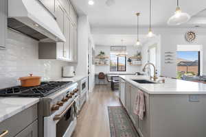 Kitchen with a sink, white appliances, a healthy amount of sunlight, under cabinet range hood, and gray cabinetry