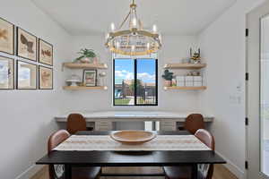 Dining space featuring baseboards, an inviting chandelier, wood finished floors, and built in study area