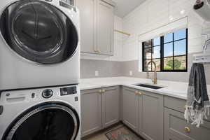 Laundry area with a sink, cabinet space, and stacked washer / drying machine