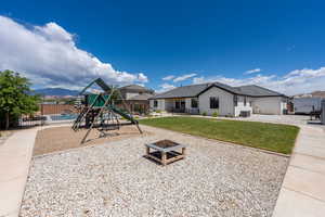 Communal playground featuring fence, a patio, a lawn, and an outdoor fire pit