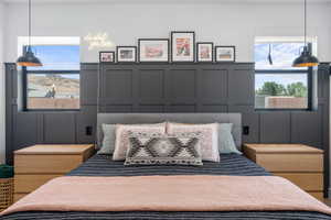 Bedroom featuring wainscoting, multiple windows, and a decorative wall