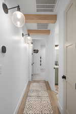 Hallway with a sink, baseboards, light wood-type flooring, and visible vents