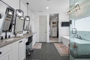 Full bath featuring a walk in closet, tile patterned flooring, a sink, a freestanding tub, and visible vents