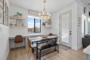 Dining space with an inviting chandelier, built in desk, visible vents, and light wood-type flooring