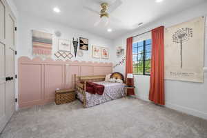 Carpeted bedroom with visible vents, recessed lighting, ceiling fan, and a decorative wall