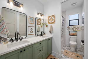 Full bathroom with baseboards, double vanity, toilet, and a sink