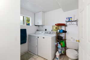 Washroom featuring light tile patterned floors, laundry area, washer and clothes dryer, and a textured ceiling