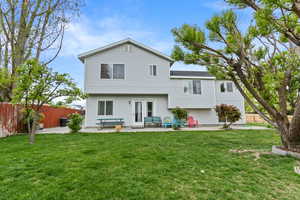 Rear view of house featuring a lawn, fence, and a patio area
