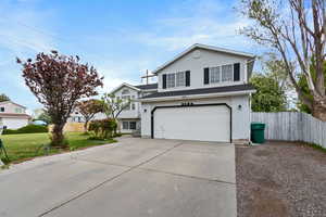 View of front of house with fence, an attached garage, a front lawn, brick siding, and driveway