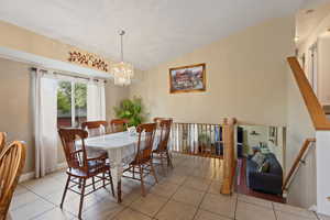 Dining area featuring tile patterned floors, a chandelier, baseboards, and lofted ceiling
