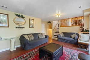 Living area with visible vents, baseboards, wood finished floors, and stairway