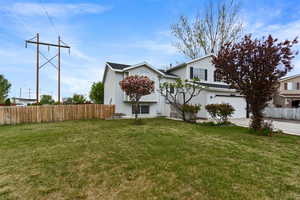 Exterior space featuring fence, an attached garage, concrete driveway, and a front yard