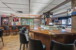 Bar with a dry bar, a drop ceiling, wood finished floors, and visible vents