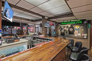 Bar featuring wooden walls, a community bar, and a drop ceiling