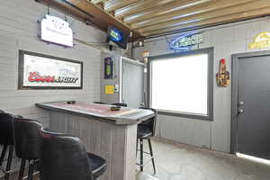 Bar featuring wood walls and unfinished concrete floors