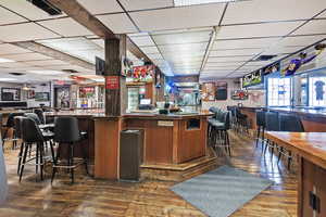 Bar featuring a bar, wood-type flooring, and a drop ceiling