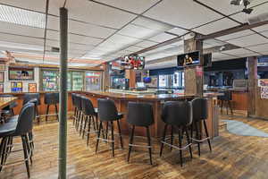 Bar with visible vents, a community bar, wood finished floors, and a paneled ceiling