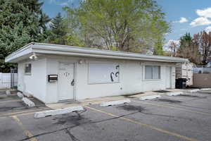 View of front facade featuring brick siding, uncovered parking, and fence