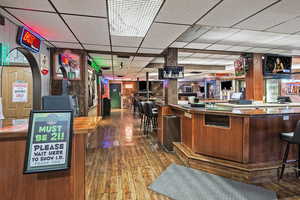 Bar featuring a bar, a drop ceiling, wood-type flooring, and visible vents